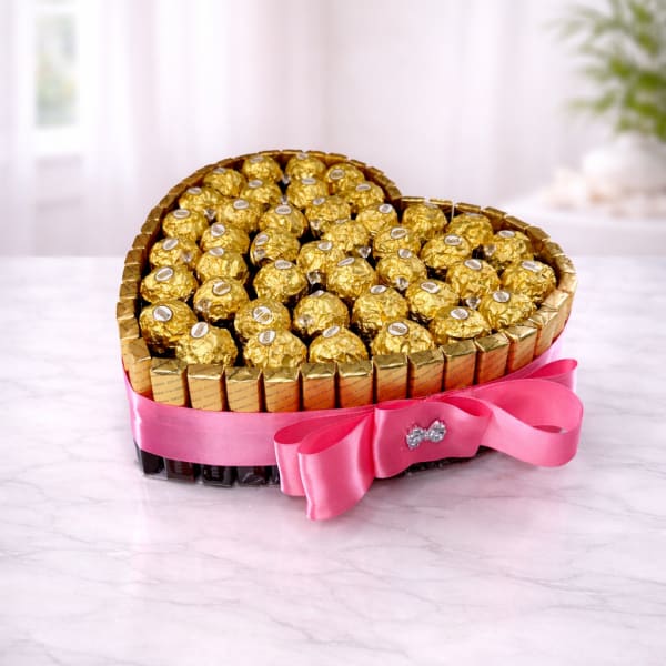Heart-shaped arrangement of gold-wrapped chocolates with a pink ribbon bow