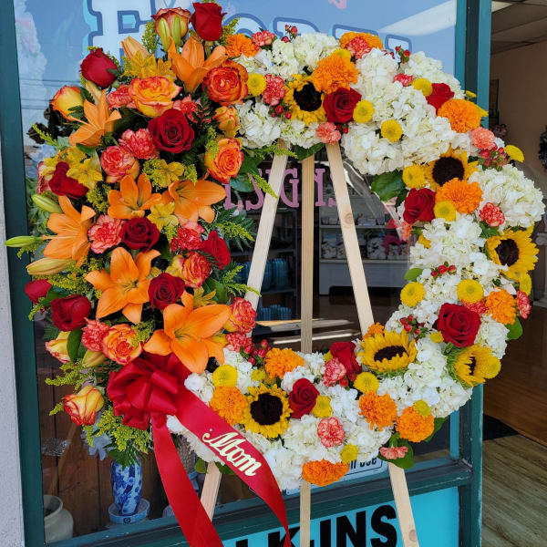 Large floral wreath on an easel with red, orange, yellow, and white flowers