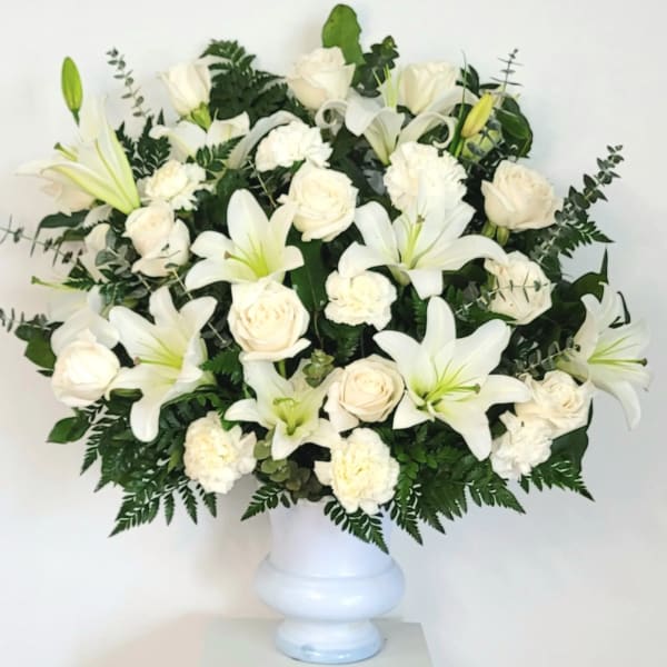 White lilies and roses arranged in a white vase