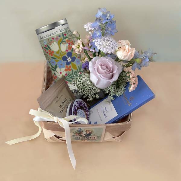 Gift basket with pastel flowers, tea, soap, and chocolate