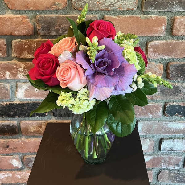 Bouquet of red, peach, and purple flowers in a glass vase