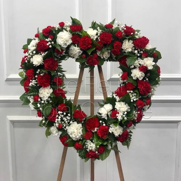 Heart-shaped wreath of red and white carnations on a wooden easel