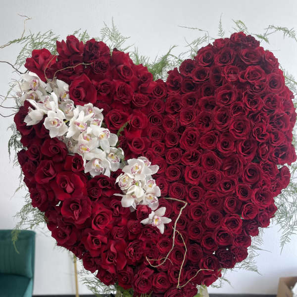 Heart-shaped red rose arrangement with white orchids on an easel