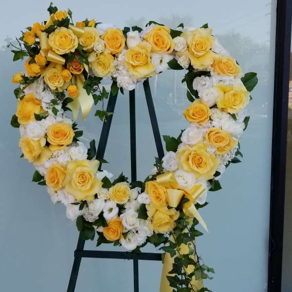 Heart-shaped floral wreath of yellow and white roses on an easel