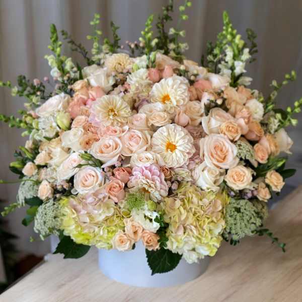 Large pastel flower arrangement in a white vase with roses and daisies