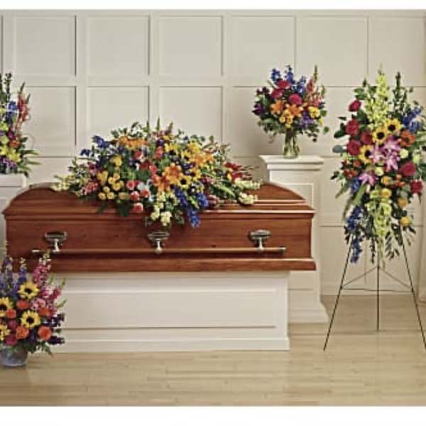 Colorful funeral casket spray with standing floral arrangements around a coffin