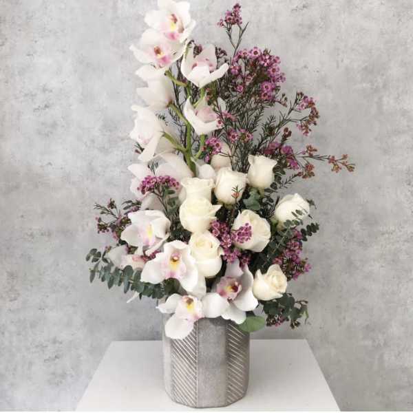 White roses and orchids in a silver vase