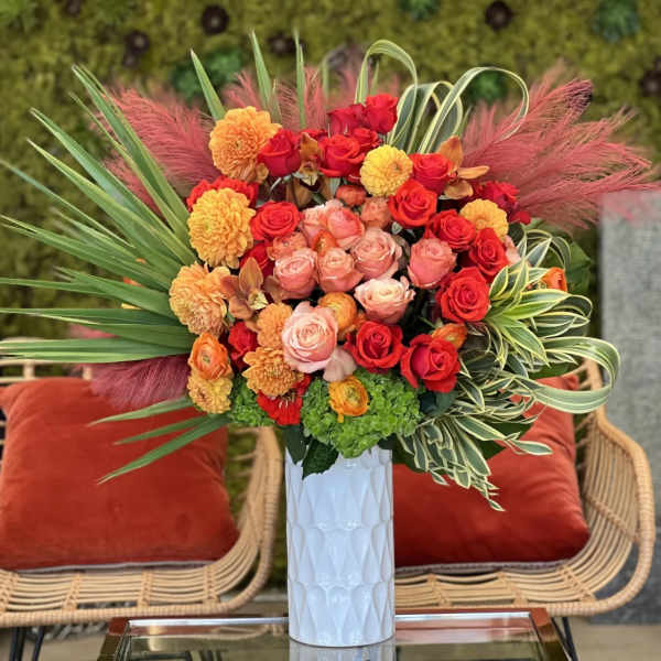 Bright bouquet of red, pink, and orange flowers in a white vase
