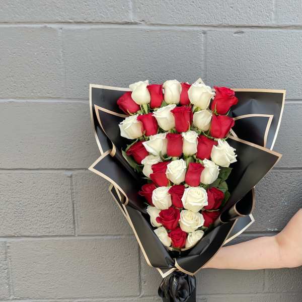 Bouquet of red and white roses wrapped in black paper