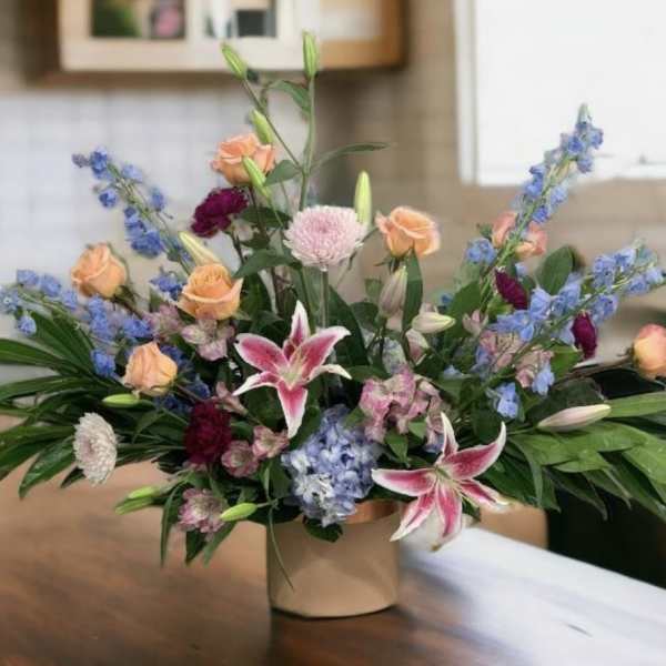 Mixed bouquet in a beige vase with pink lilies and peach roses