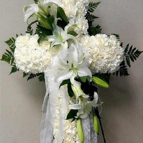 White funeral spray with lilies and carnations on a stand