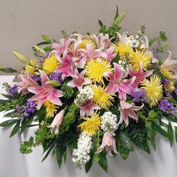 Large casket spray with pink lilies, yellow chrysanthemums, and purple accents