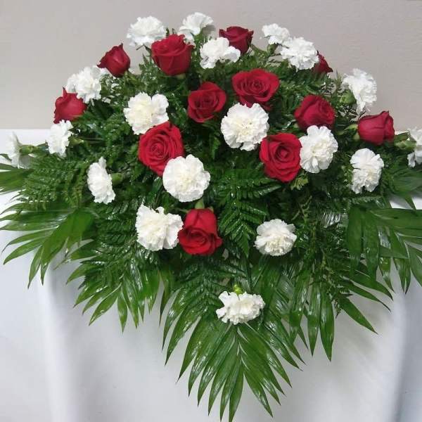 Red roses and white carnations arranged with palm fronds
