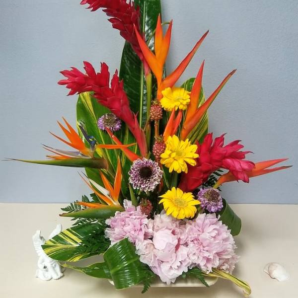 Tropical flower arrangement with red ginger, bird of paradise, yellow daisies, and pink hydrangeas