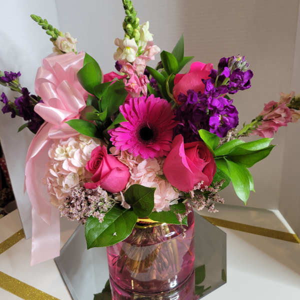 Pink and purple mixed bouquet in a pink glass vase with a ribbon