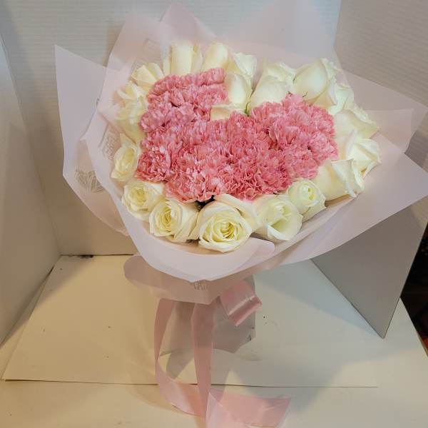 Pink carnations and white roses in pale pink wrapping with a ribbon