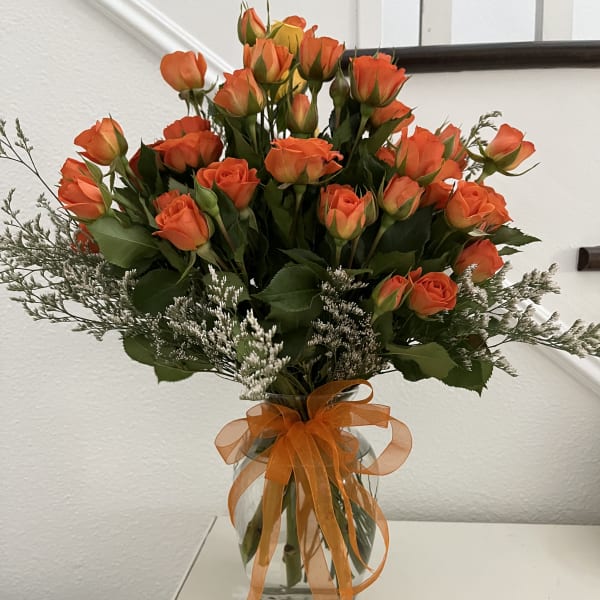 Orange roses in a glass vase with an orange ribbon