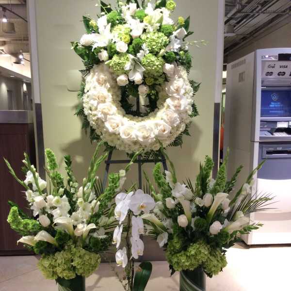 Large white and green funeral floral display with wreaths and standing arrangements