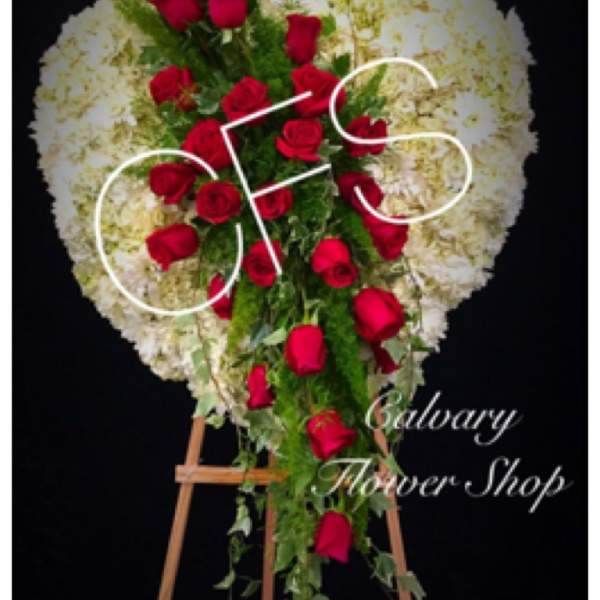 Heart-shaped standing spray of red roses and white flowers on an easel