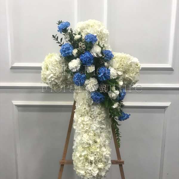 White and blue floral cross on a wooden easel