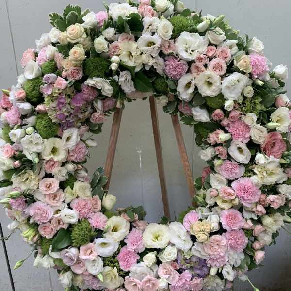 Large pastel floral wreath on an easel with pink and white blooms