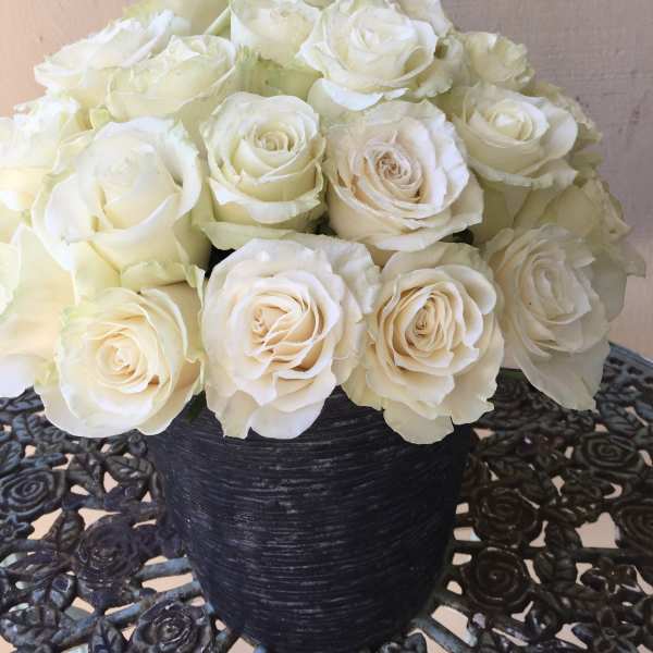 Compact arrangement of ivory roses in a black textured vase