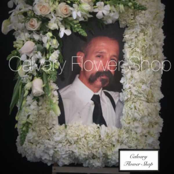Large white floral funeral frame with a portrait in the center