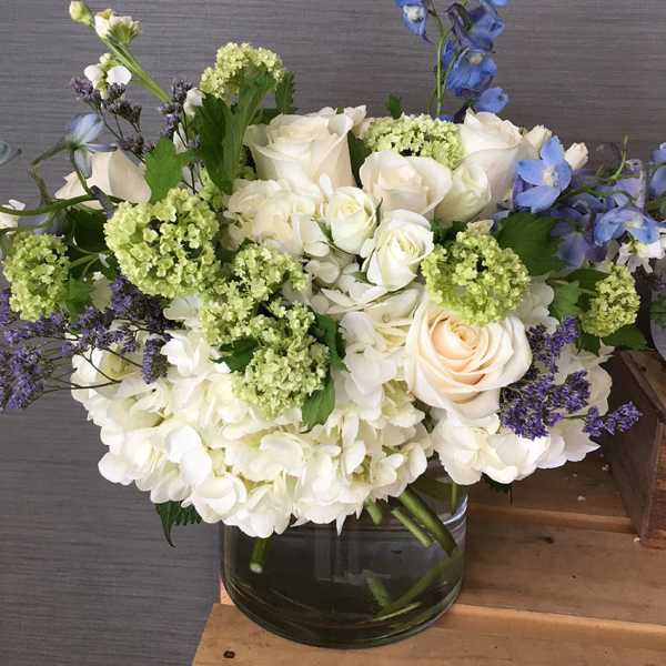 White and blue floral arrangement in a glass vase