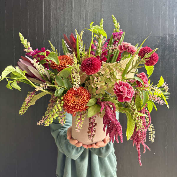 Large mixed bouquet in a beige vase with pink and orange blooms