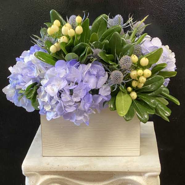 Lavender hydrangeas with yellow berries in a wooden box