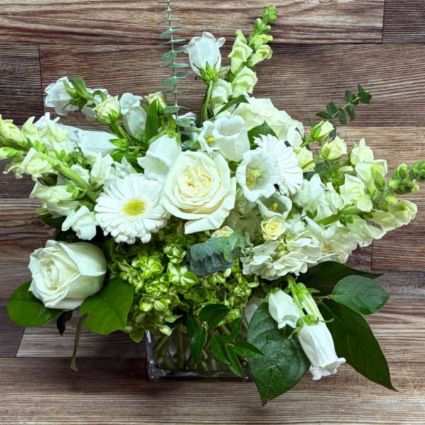 White roses and snapdragons arranged in a square glass vase