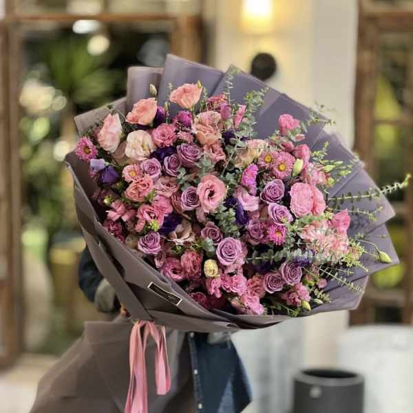 Large bouquet of pink and lavender flowers wrapped in mauve paper