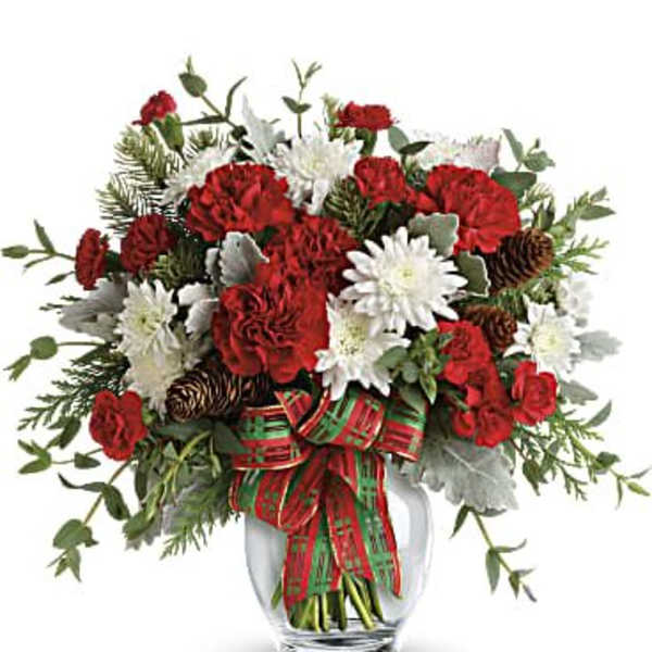 Red and white flowers arranged in a clear glass vase with a plaid ribbon