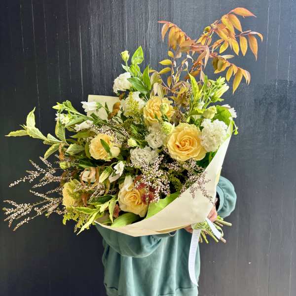 Bouquet of yellow roses and white flowers with autumn-toned foliage