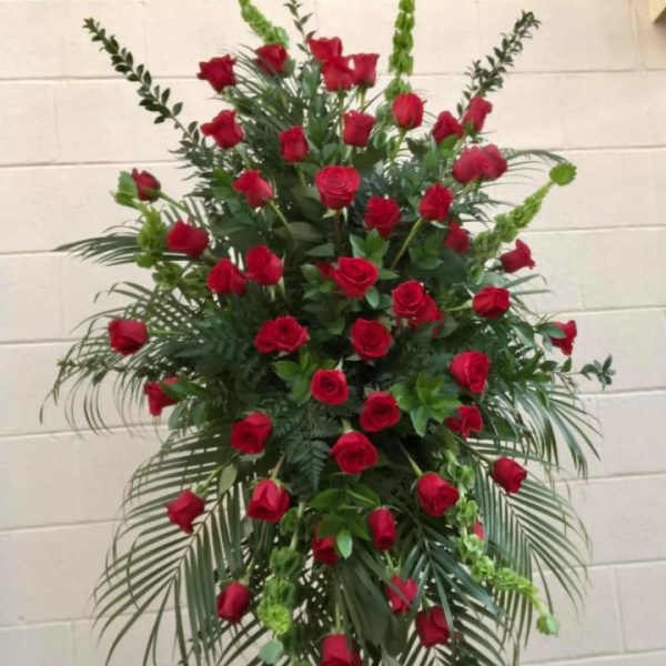Tall standing arrangement of red roses with greenery