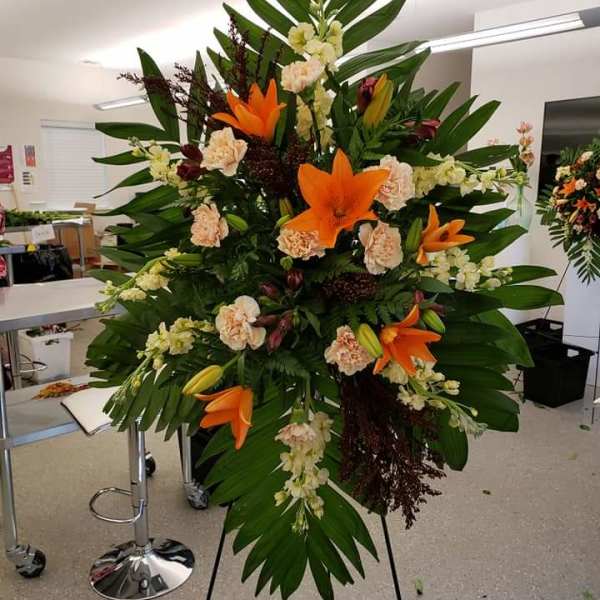 Tall standing floral spray with orange lilies and pale carnations