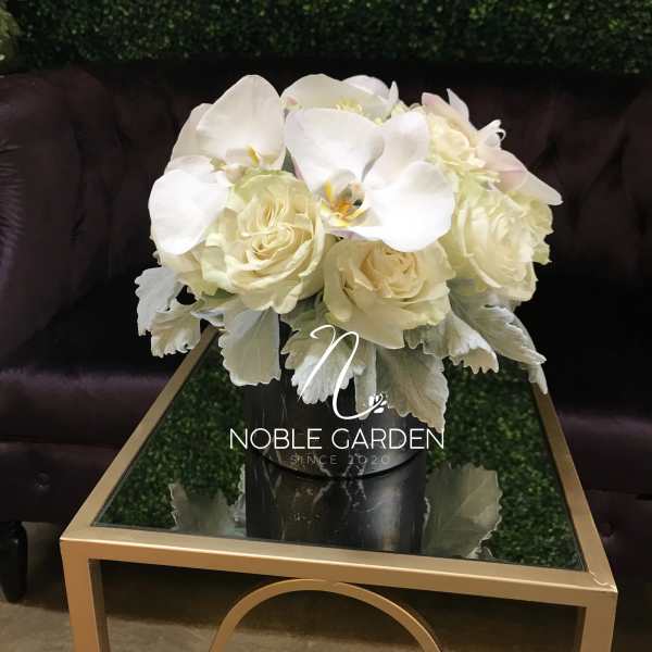 White roses and orchids arranged in a black vase