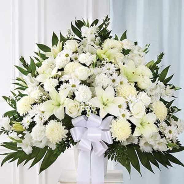 Large white funeral spray with lilies, chrysanthemums, and a ribbon