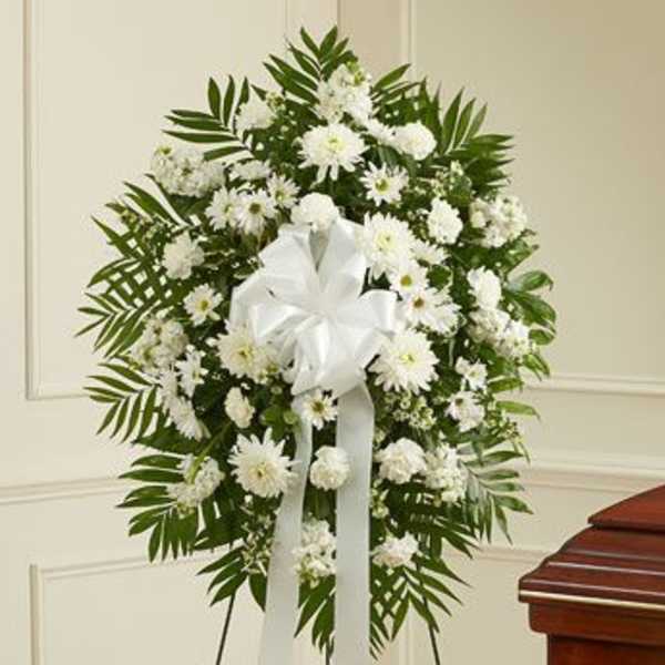 White funeral wreath with a satin bow on a stand