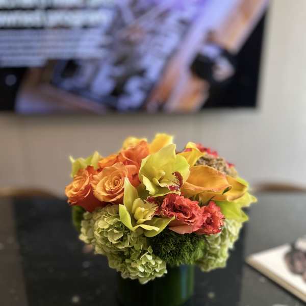 Orange roses and yellow orchids in a green vase