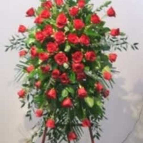 Standing spray of red roses on a white easel