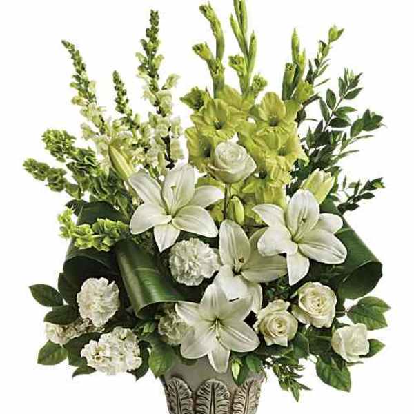 White lilies and roses in a decorative pedestal vase with green accents