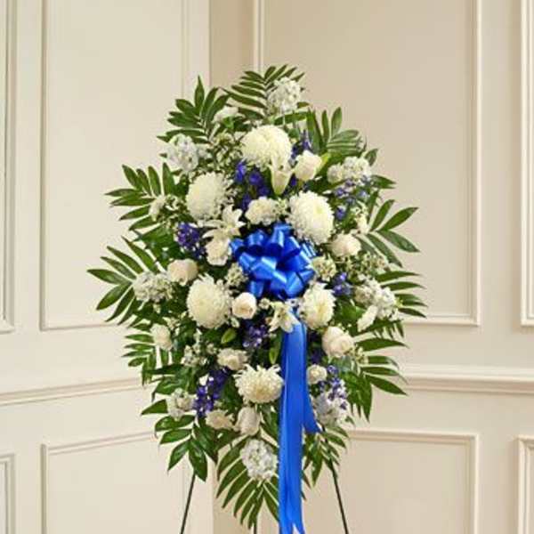 Standing floral spray of white and blue flowers with a blue ribbon