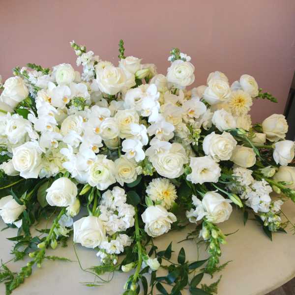 Large white floral arrangement with roses and orchids on a table