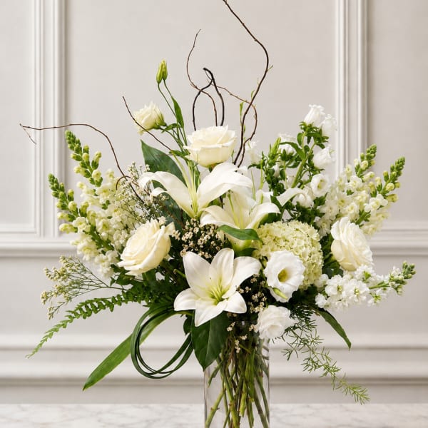 White lilies and roses arranged in a clear glass vase