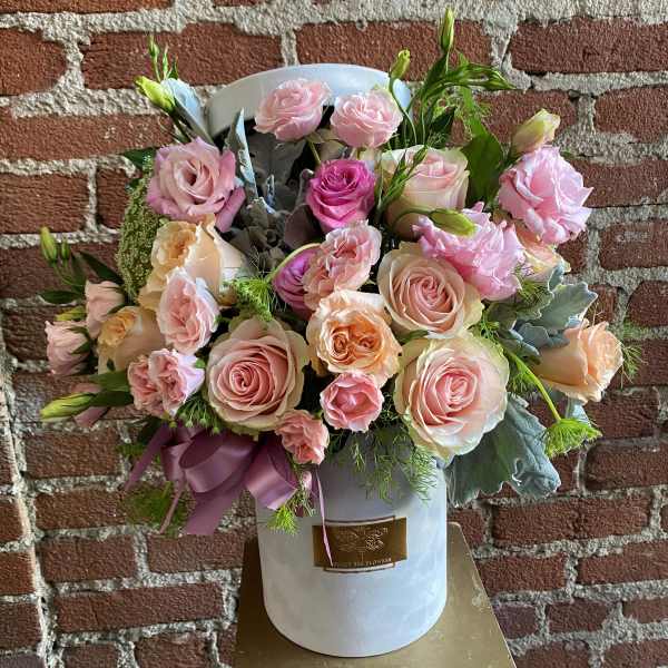 Pink and peach roses arranged in a white hat box