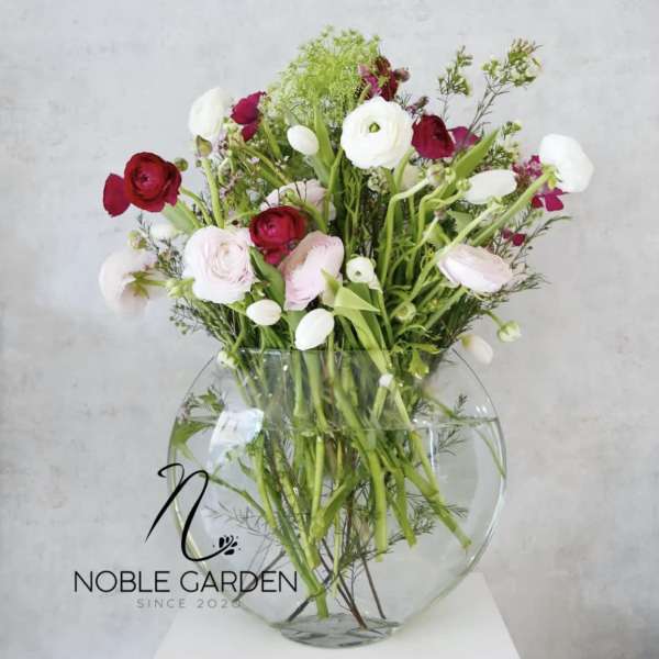 Mixed pink, red, and white flowers in a clear round vase