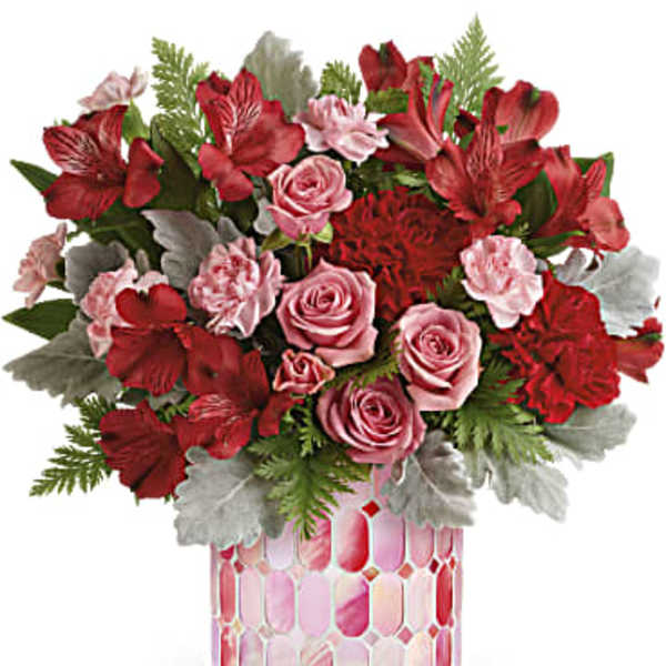 Pink and red floral arrangement in a patterned glass vase