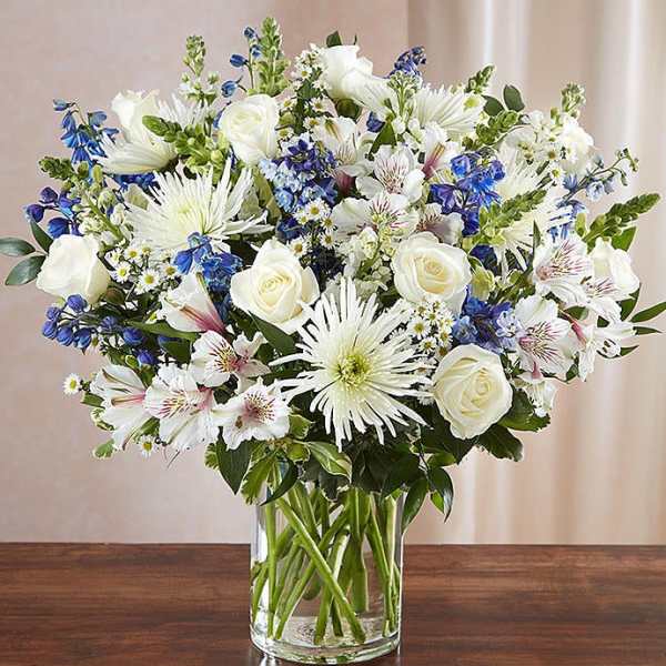White and blue mixed bouquet in a clear glass vase
