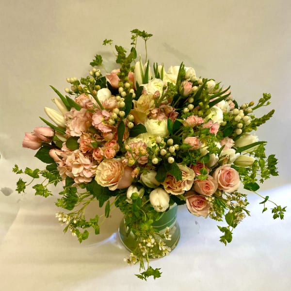 Blush and white floral arrangement in a green vase